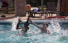 两名男生在校园体育中心室外游泳池打水上篮球.